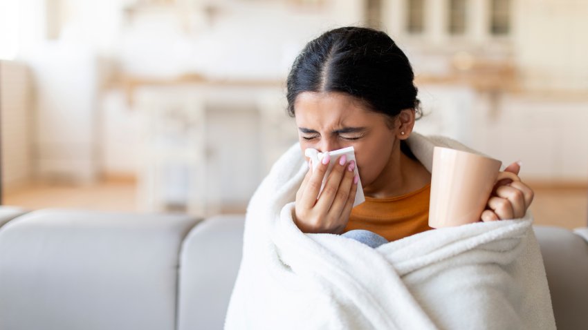 Cold And Flu Symptoms . Sick indian woman covered in blanket blowing nose