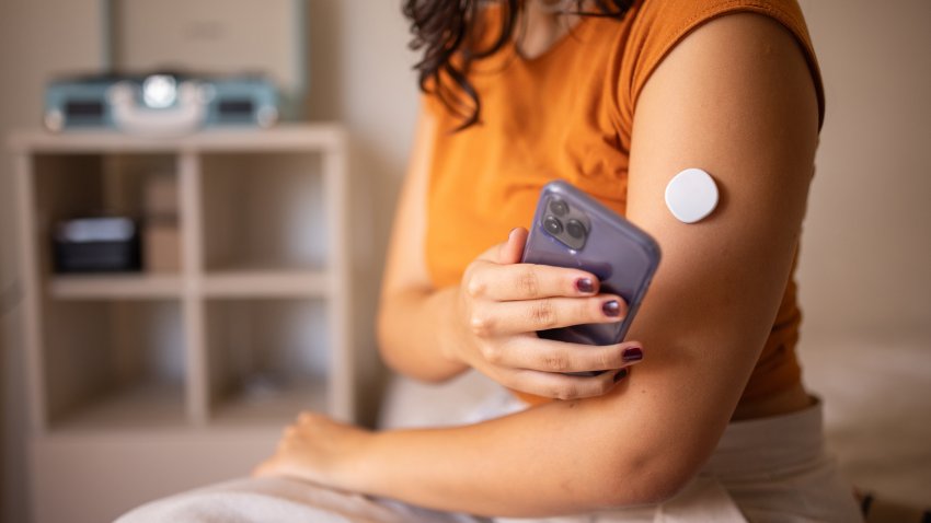 Young diabetic patient monitoring glucose level with remote sensor at home, she has a glucose monitor on her arm.