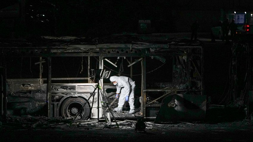 An Israeli police officer inspects the scene of one of a series of bus explosions in what authorities said appeared to be a militant attack in Bat Yam, central Israel, Thursday, Feb. 20, 2025.