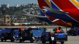 A baggage handler drives a cart full of luggage near Southwest Airlines jets at San Diego International Airport on March 4, 2025 in San Diego, California. 