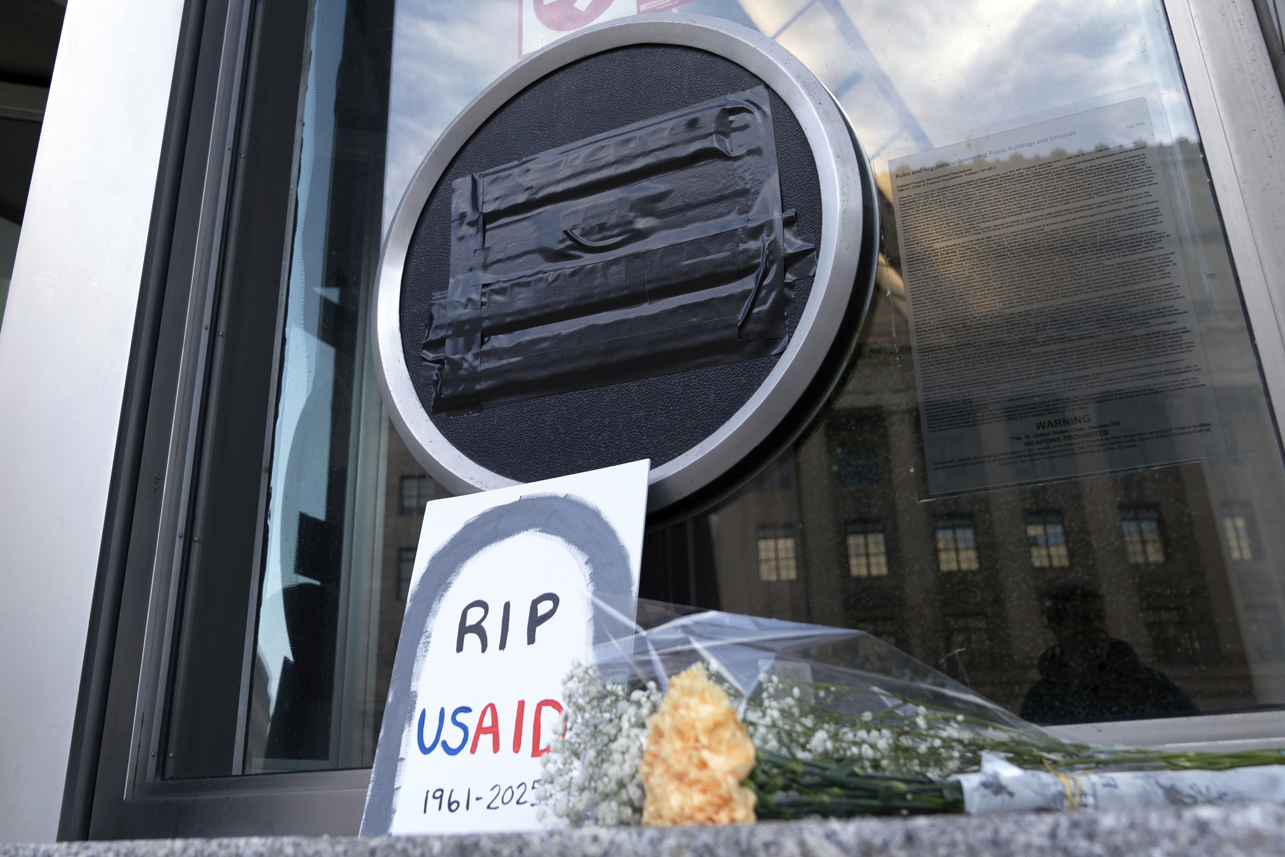 Flowers and a sign are placed outside the headquarters of the U.S. Agency for International Development