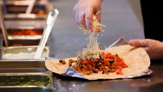 A employee sprinkles cheese on a burrito at a Chipotle Mexican Grill Inc. restaurant in Hollywood, California, U.S., on Tuesday, July 16, 2013. Chipotle Mexican Grill Inc. is scheduled to release earnings data on July 18. Photographer: Patrick T. Fallon/Bloomberg via Getty Images