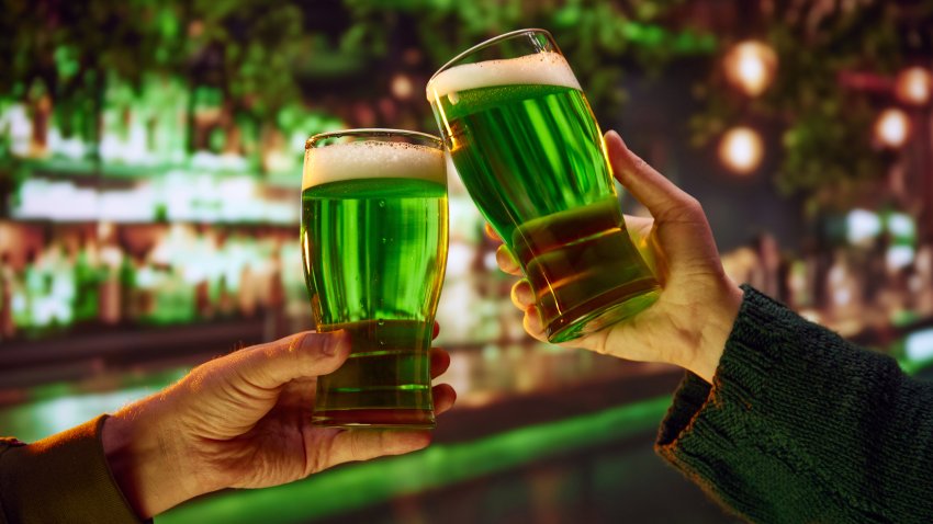 Two people sitting in pub at bar counter and drinking craft green traditional beer