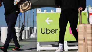 Travelers walk past a sign pointing toward the Uber rideshare vehicle pickup area at Los Angeles International Airport (LAX) on February 8, 2023 in Los Angeles, California.