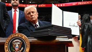 US President Donald Trump holds an executive order he just signed during the inaugural parade inside Capital One Arena, in Washington, DC, on Jan. 20, 2025. 