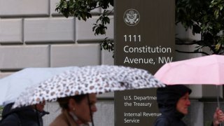 People walk in the rain past the Internal Revenue Service (IRS) building in Washington, D.C., U.S., April 11, 2025.