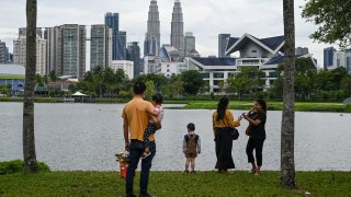 Visitors look at the city skyline from a park in Kuala Lumpur on September 30, 2021. (Photo by Mohd RASFAN / AFP) (Photo by MOHD RASFAN/AFP via Getty Images)