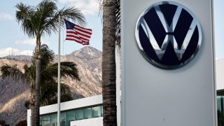 An American flag flies beyond the Volkswagen logo displayed at a Volkswagen dealership on April 4, 2025 in Pasadena, California.