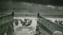 Assault troops approach Omaha Beach, June 6, 1944. The original caption for this iconic US Coast Guard image reads "INTO THE JAWS OF DEATH — Down the ramp of a Coast Guard landing barge Yankee soldiers storm toward the beach-sweeping fire of Nazi defenders in the D-Day invasion of the French Coast. Troops ahead may be seen lying flay under the deadly machinegun resistance of the Germans. Soon the Nazis were driven back under the overwhelming invasion forces thrown in from Coast Guard and Navy amphibious craft."