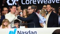 CoreWeave founders Brian Venturo, at left in sweatshirt, and Mike Intrator slap five after ringing the opening bell at Nasdaq headquarters in New York on March 28, 2025.