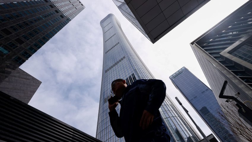 A man walks past buildings at Central Business District (CBD) in Beijing, China April 8, 2025. 