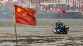 Shipping containers and gantry cranes beyond a fishing boat near the Yangshan Deepwater Port in Shanghai, China, on Wednesday, Dec. 6, 2023.