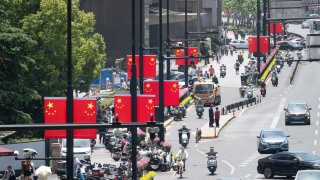 SHANGHAI, CHINA – APRIL 29: Pedestrians walk by lampposts decorated with Chinese national flags prior to May Day holiday on April 29, 2025 in Shanghai, China. (Photo by Wang Gang/VCG via Getty Images)