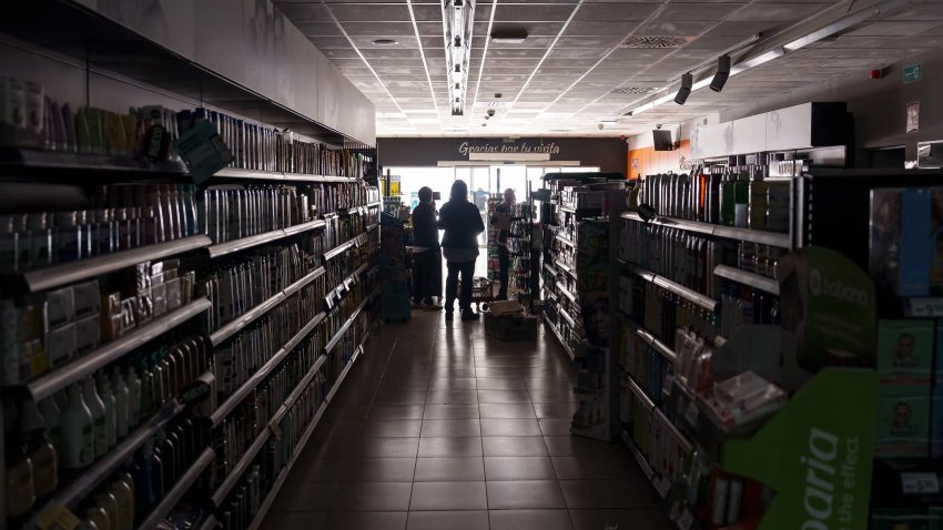 Employees stand inside a supermarket without lights in Burgos on April 28, 2025, during a massive power cut affecting the entire Iberian peninsula and the south of France.
