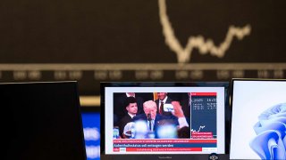 US President Trump can be seen on a screen at the Frankfurt Stock Exchange in front of the DAX curve.