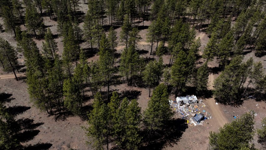 Debris lies scattered around a trailer at a homeless encampment in Deschutes National Forest, Thursday, May 1, 2025, near Bend, Ore.