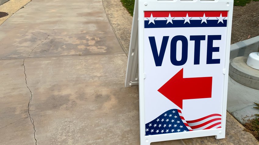 Red, white and blue sign with an arrow indicating where to go to cast or leave a ballot.