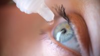 Drops from vial dripping into woman eye closeup. Conjunctivitis treatment concept
