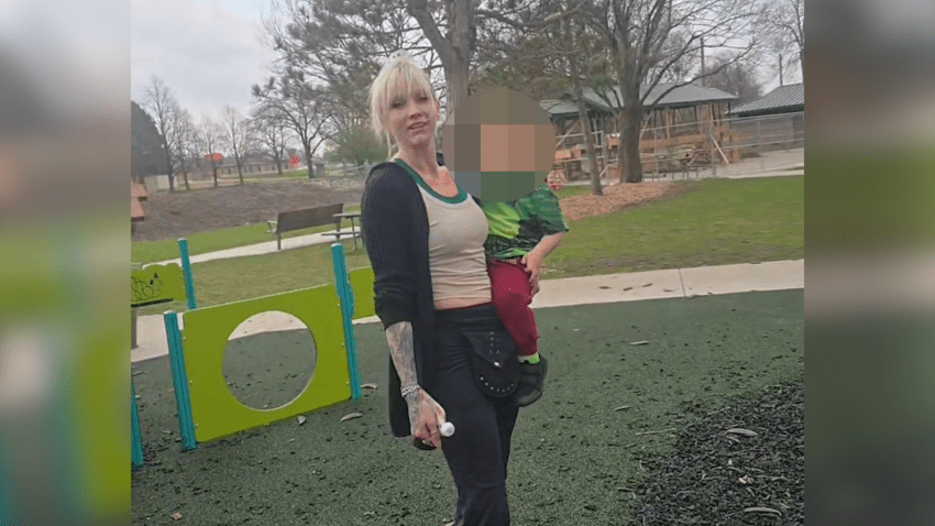 Woman stands in playground with child