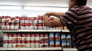 A worker arranges cans of Campbell’s soup on a supermarket shelf in San Rafael, California.