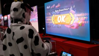 An attendee wearing a cow costume while playing Mario Kart World by Nintendo Switch 2 during the Nintendo Switch 2 Experience at the Excel London international exhibition and convention centre in London on April 11, 2025.