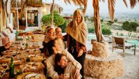 Wide shot of friends and family enjoying dinner and sunset during destination wedding reception at luxury villa in Morocco