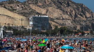 Tourists and locals enjoy a warm spring day with high temperatures in El Postiguet Beach.