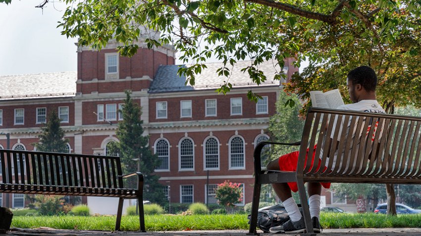 FILE - With the Founders Library in the background, a young man reads on Howard University campus July 6, 2021, in Washington.
