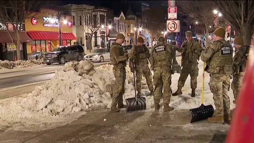 National Guard members holding shovels clear a path to a bus stop on H Street NE.